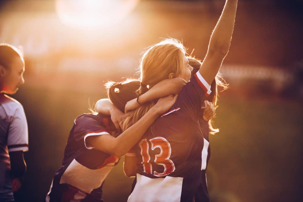 Jubelnde Fußballspielerinnen im Sonnenuntergang