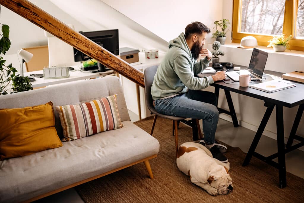 Mann arbeitet von zu Hause mit schlafendem Hund