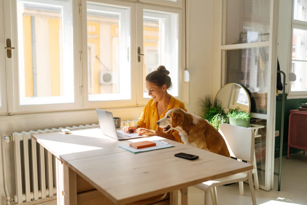 Frau arbeitet am Laptop mit Hund