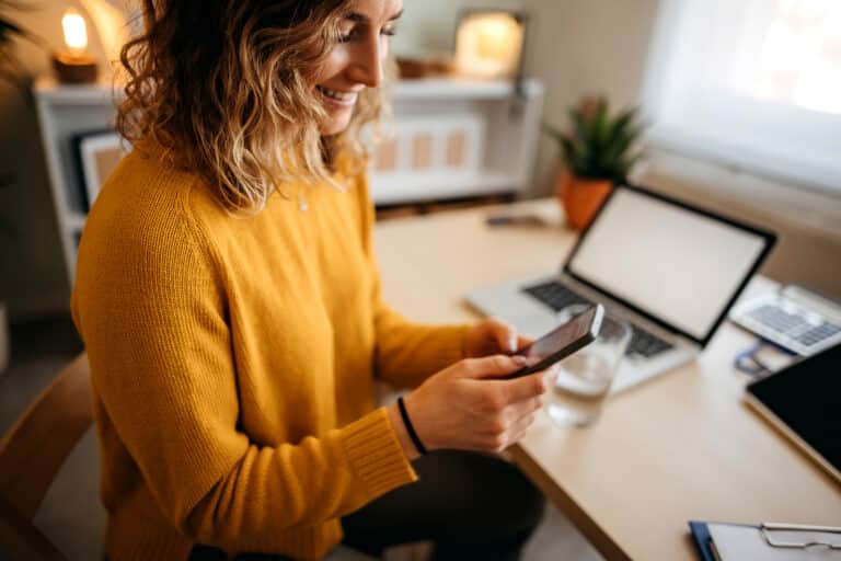 Person am Schreibtisch mit Smartphone